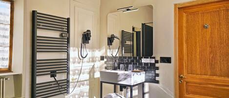 Un baño con toallero, espejo, lavabo y puerta.