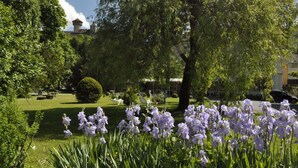 Un jardin avec une pelouse, des arbres et un kiosque.