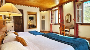 A hotel room with a large bed, a desk, a chair, and a window with a view of a mountain. - Hotel du Parc - Manoir du Baron Blanc (Faverges-Seythenex)