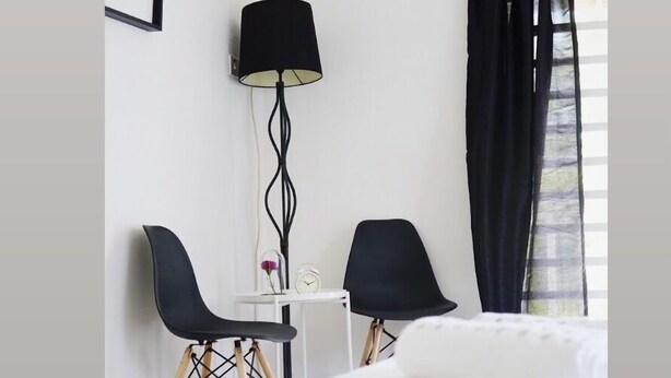 A hotel room with a bed, two chairs, a small table with a clock, a lamp, and a window with curtains. - Cozy Scandinavian Bungalow near KLIA & Sepang F1 (KOTA SERIEMAS)