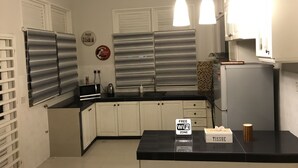 A modern kitchen with white cabinets, a black countertop, and a sign indicating a free WiFi zone. - Cozy Scandinavian Bungalow near KLIA & Sepang F1 (KOTA SERIEMAS)