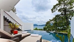 Ett modernt utomhusområde med loungekänsla, en pool, en trappa och utsikt över havet.
