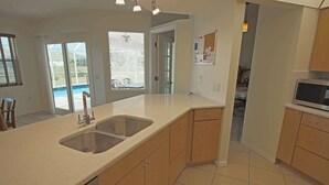 A kitchen with a large island, double sink, and wooden cabinets.