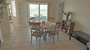 A dining area with a table and chairs, a bookshelf, and a door leading outside.