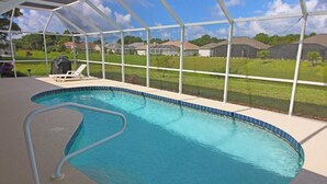 An indoor swimming pool with a clear view of the surrounding area, including houses and greenery.