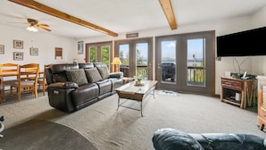 Ein Wohnzimmer mit Ledersofa, Couchtisch, Fernseher und großen Fenstern mit Blick.