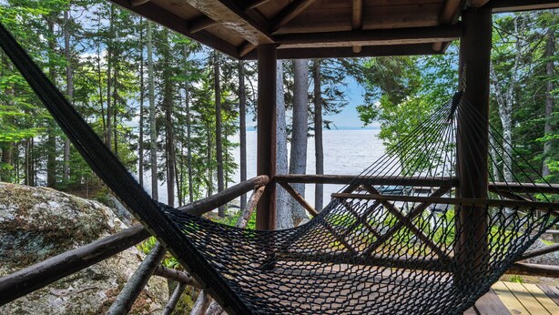A hammock under a wooden structure with a view of a forest and a body of water. - Rock Ledge - Relax & Renew in turn-of-century log cabin with side cabin (Rangeley)
