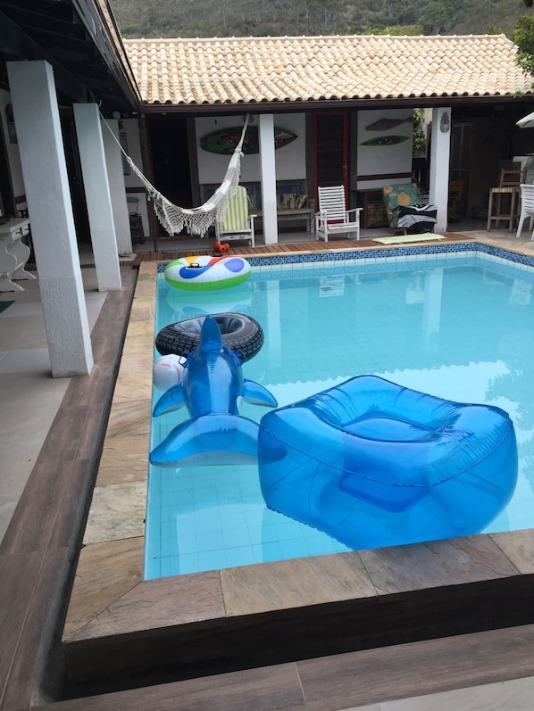 A swimming pool with inflatable toys, a hammock, and outdoor furniture.