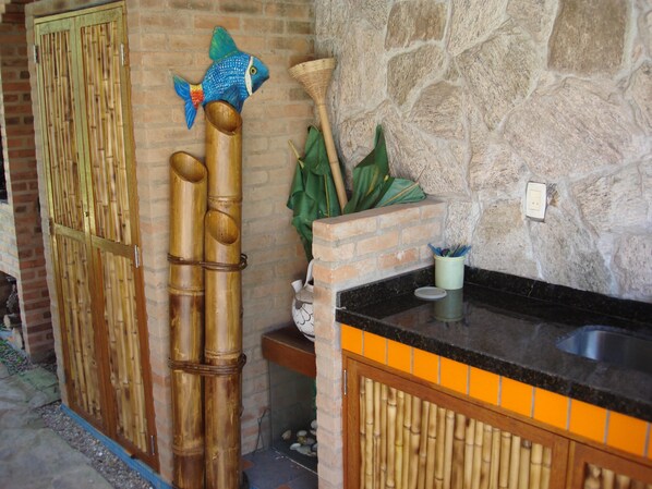 Bagno con decorazione a forma di pesce in bambù, parete in pietra, parete in mattoni, porta in bambù e un piano d'appoggio nero.