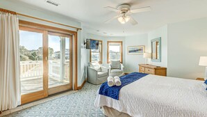 Ein Hotelzimmer mit einem großen Bett, zwei Sesseln, einem Deckenventilator und einem Balkon mit Blick.