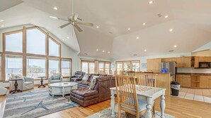 Ein geräumiges Wohnzimmer mit hohen Decken, großen Fenstern und Blick ins Freie.