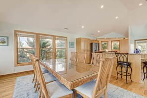 A spacious kitchen with a large island, wooden cabinets, and a dining area with a glass-top table and chairs.