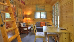 A cozy cabin interior with a wooden interior, a dining area, a sofa, and a ladder. - Greenvale Cove 8 - Greenvale Cove cottage community on Rangeley Lake (Rangeley)