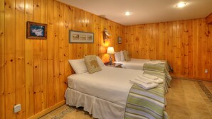 A room with wooden paneling, two beds with white bedding, a lamp, and a framed picture on the wall. - Saddleback Lake Lodge 33 | Close to Saddleback (Rangeley)