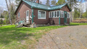 A log cabin with a green roof, a porch, and a small front yard. - Rangeley Manor A | Nice Cottage Close to Shared Waterfront on Rangeley Lake (Rangeley)