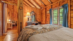 A wooden cabin room with a bed, a desk, and a window with curtains. - 🐾Kadel - Maine log home on Mooselookmeguntic Lake filled with rustic charm, dog friendly (Oquossoc)