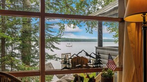 A view from a window overlooking a lake with boats, a bear, and an American flag decoration. - 🐾Kadel - Maine log home on Mooselookmeguntic Lake filled with rustic charm, dog friendly (Oquossoc)