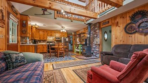 Un vaste espace de vie doté d’une cheminée, de meubles en bois et d’une mezzanine avec balcon.