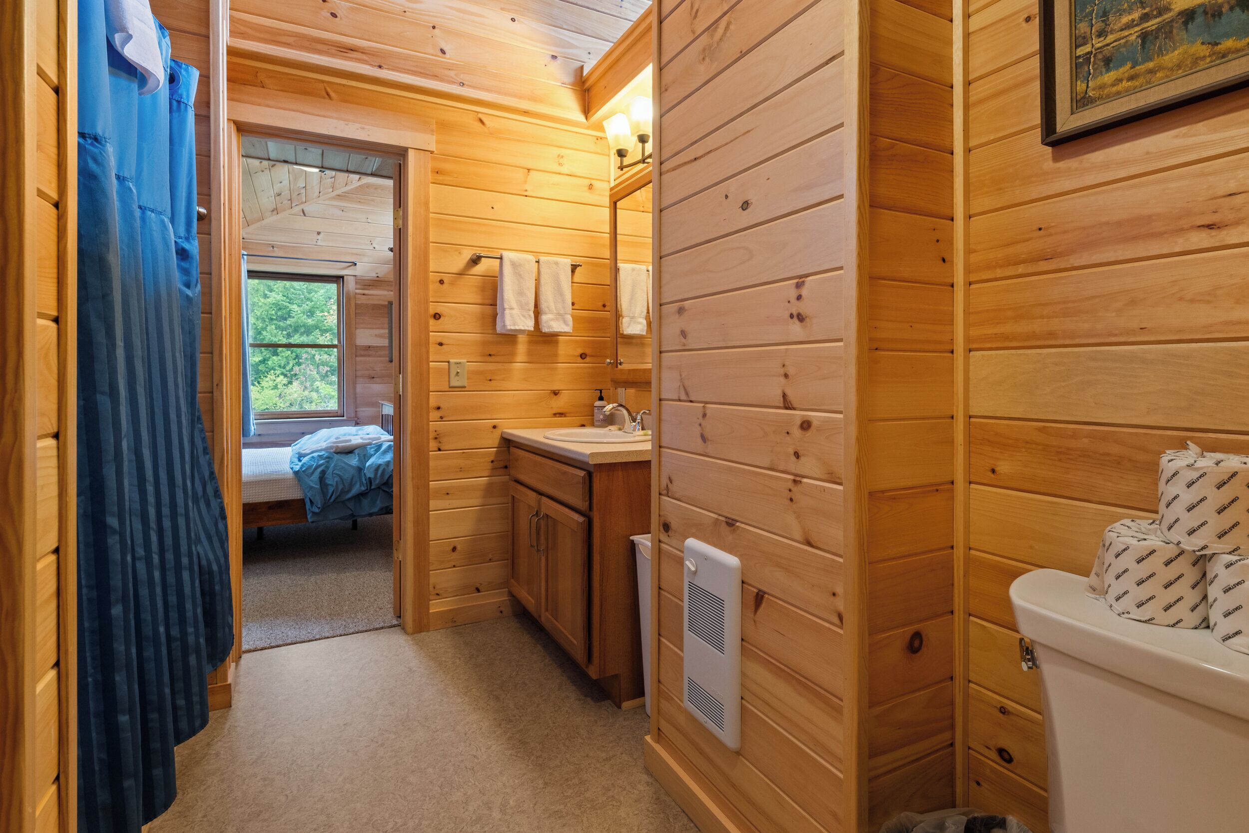 A wooden cabin bathroom with a sink, toilet, and a small window.