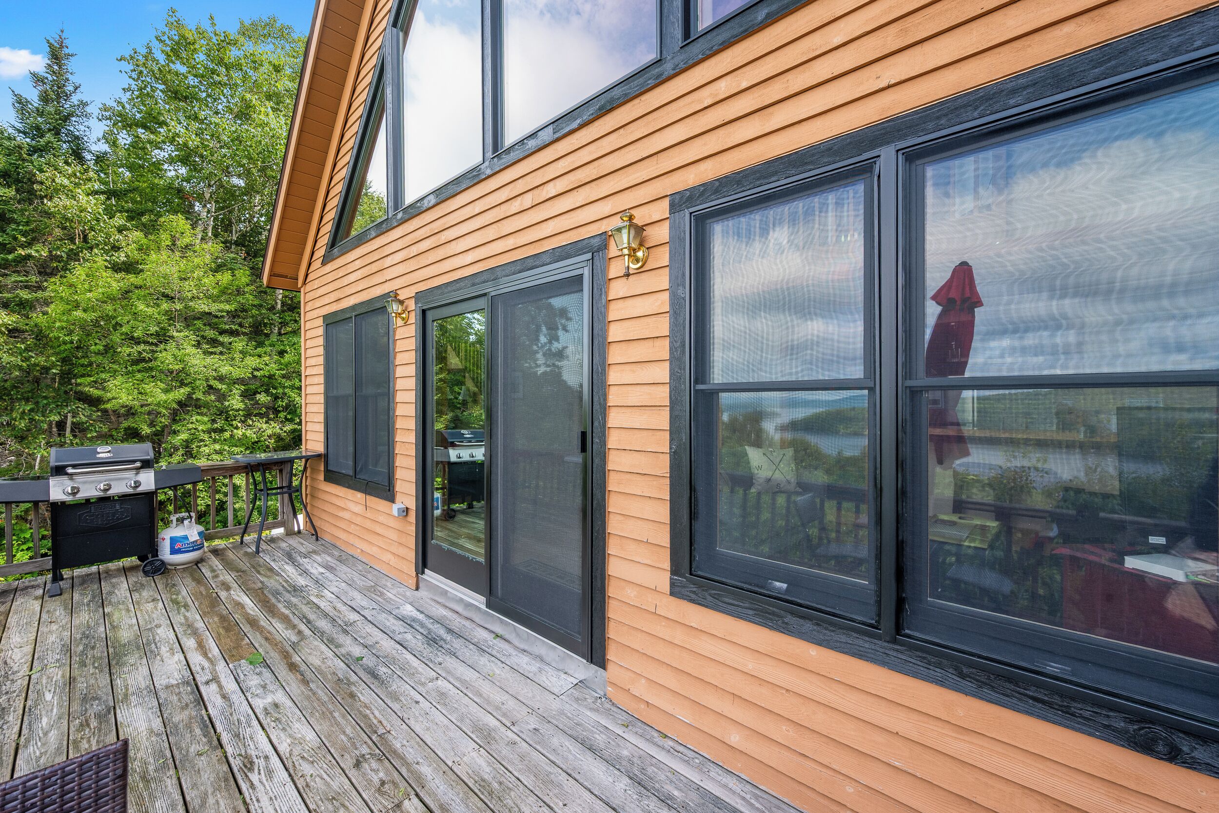 A wooden deck with a grill and outdoor furniture.