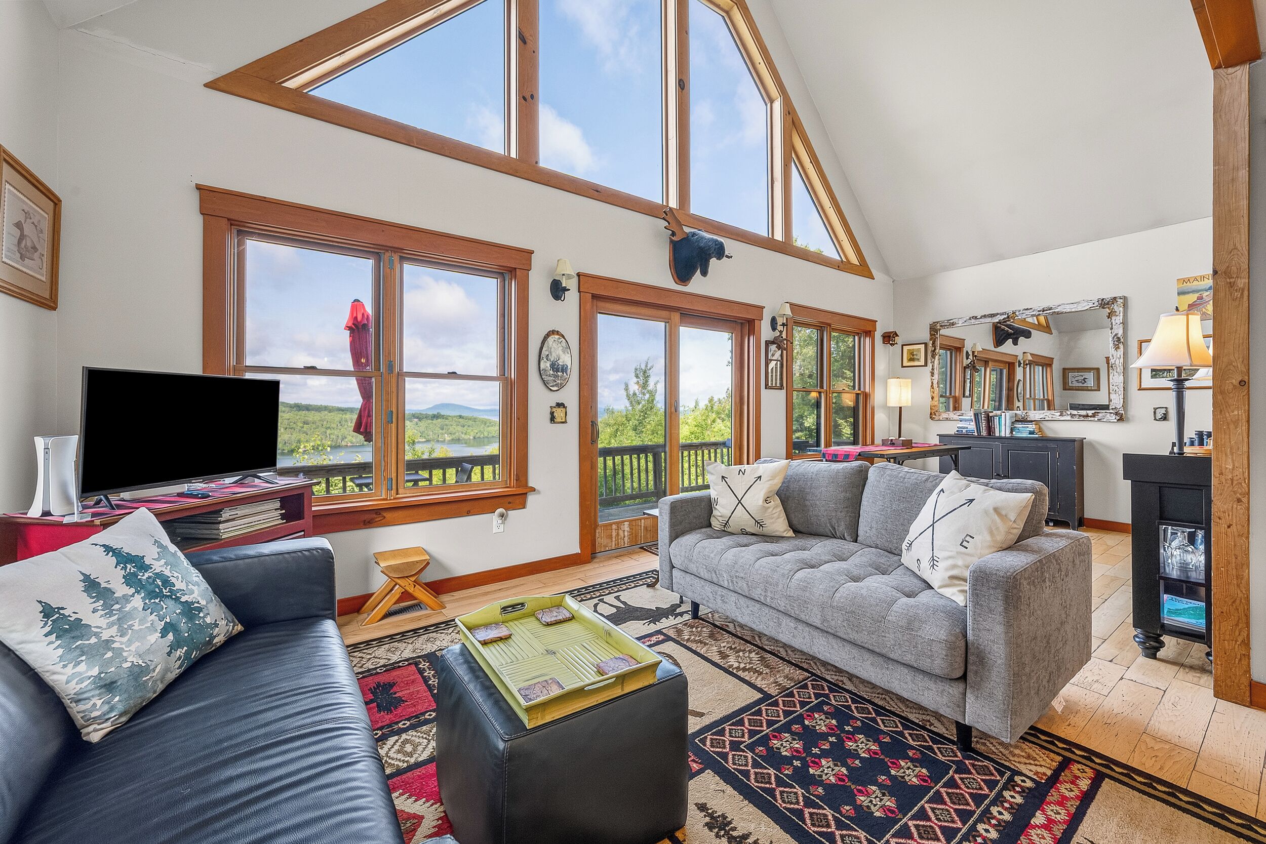 A spacious living room with a large window, a flat-screen TV, and a cozy seating area with a sofa and ottoman.