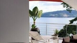 Ein modernes Interieur mit einer großen Steinschale, einem weißen Stuhl und Blick auf einen See und Berge.