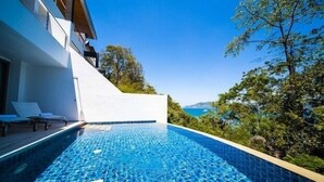 Ein moderner Poolbereich mit klarem, blauem Wasser, umgeben von üppiger Vegetation und Blick aufs Meer.