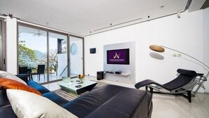 Ein modernes Wohnzimmer mit einer Couch, einem Couchtisch, einem Fernseher und einem Sessel.