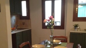Una mesa de comedor dispuesta con platos, vasos y un florero con flores.