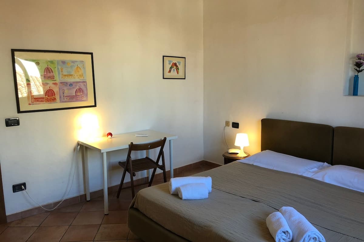 Una habitación de hotel con una cama, un escritorio, una silla y dos lámparas de noche.