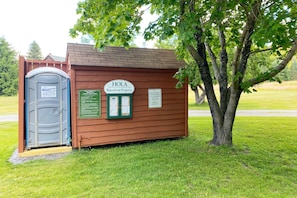 Una pequeña estructura de madera con una puerta que dice 'Brackets' y un cartel que anuncia 'HOLA Waterfront Property'.