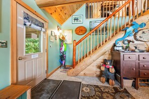 A wooden staircase with a bear decoration, a door with a window, and a wall with framed pictures.