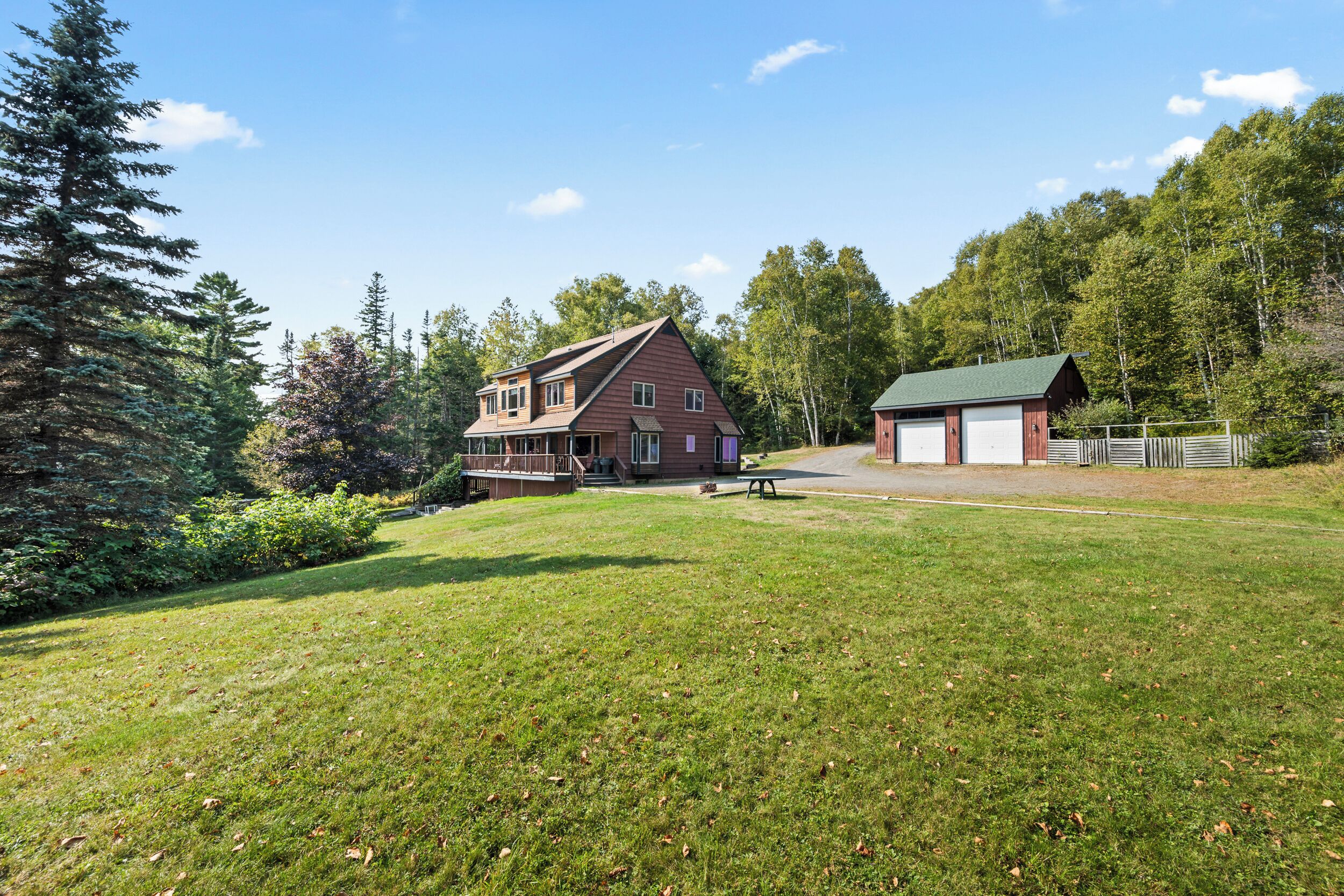 A two-story house with a large front porch, a garage, and a well-maintained lawn.