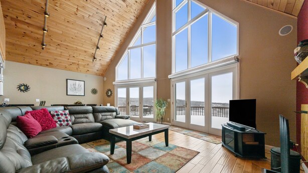 A spacious living room with a leather sofa, a coffee table, and a fireplace. - A Starry Night | Shared Waterfront | Close to Saddleback | Views (Rangeley)