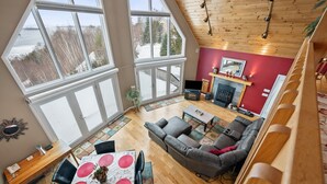 A spacious living area with a large window, a fireplace, and a cozy seating arrangement. - A Starry Night | Shared Waterfront | Close to Saddleback | Views (Rangeley)