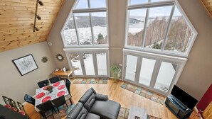 A spacious living area with a large sofa, dining table, and a television. - A Starry Night | Shared Waterfront | Close to Saddleback | Views (Rangeley)