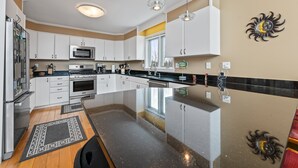 A modern kitchen with white cabinets, stainless steel appliances, and pendant lighting. - A Starry Night | Shared Waterfront | Close to Saddleback | Views (Rangeley)