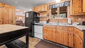 Une cuisine avec des meubles en bois, un réfrigérateur noir, une cuisinière blanche et un plan de travail en granit.