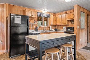 A kitchen with wooden cabinets, a black refrigerator, a stove, and a sink. - Pine Valley - Great newly renovated cabin - close to the village of Oquossoc (Rangeley)