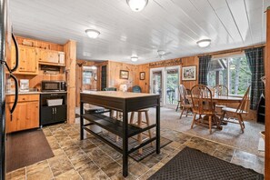 A wooden interior with a kitchen, dining area, and a fireplace.