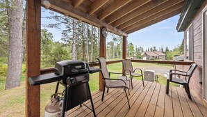 Une terrasse couverte équipée d’un barbecue, de chaises et offrant une vue sur un quartier résidentiel.