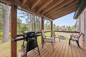 Una terrazza coperta con barbecue, sedie e vista su una zona residenziale.