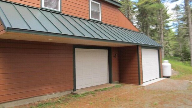 Un bâtiment à deux étages, doté d’un toit en métal et de deux portes de garage.