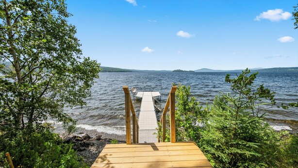 A wooden dock leading to a body of water with a clear sky.