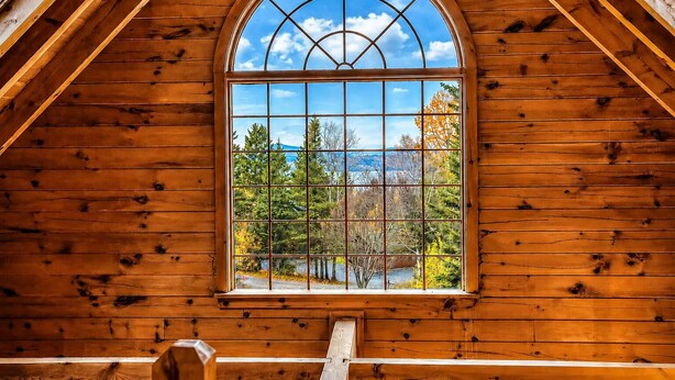 A wooden cabin with a large arched window, wooden beams, and a view of trees and mountains. - 🐾33 Loop Rd Log Cabin w/ Shared Rangeley Lake Access, Snowmobile/ATV Access, 15 min to Saddleback (Rangeley)