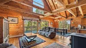 A wooden cabin interior with a loft bedroom, a dining area, and a kitchen. - 🐾33 Loop Rd Log Cabin w/ Shared Rangeley Lake Access, Snowmobile/ATV Access, 15 min to Saddleback (Rangeley)