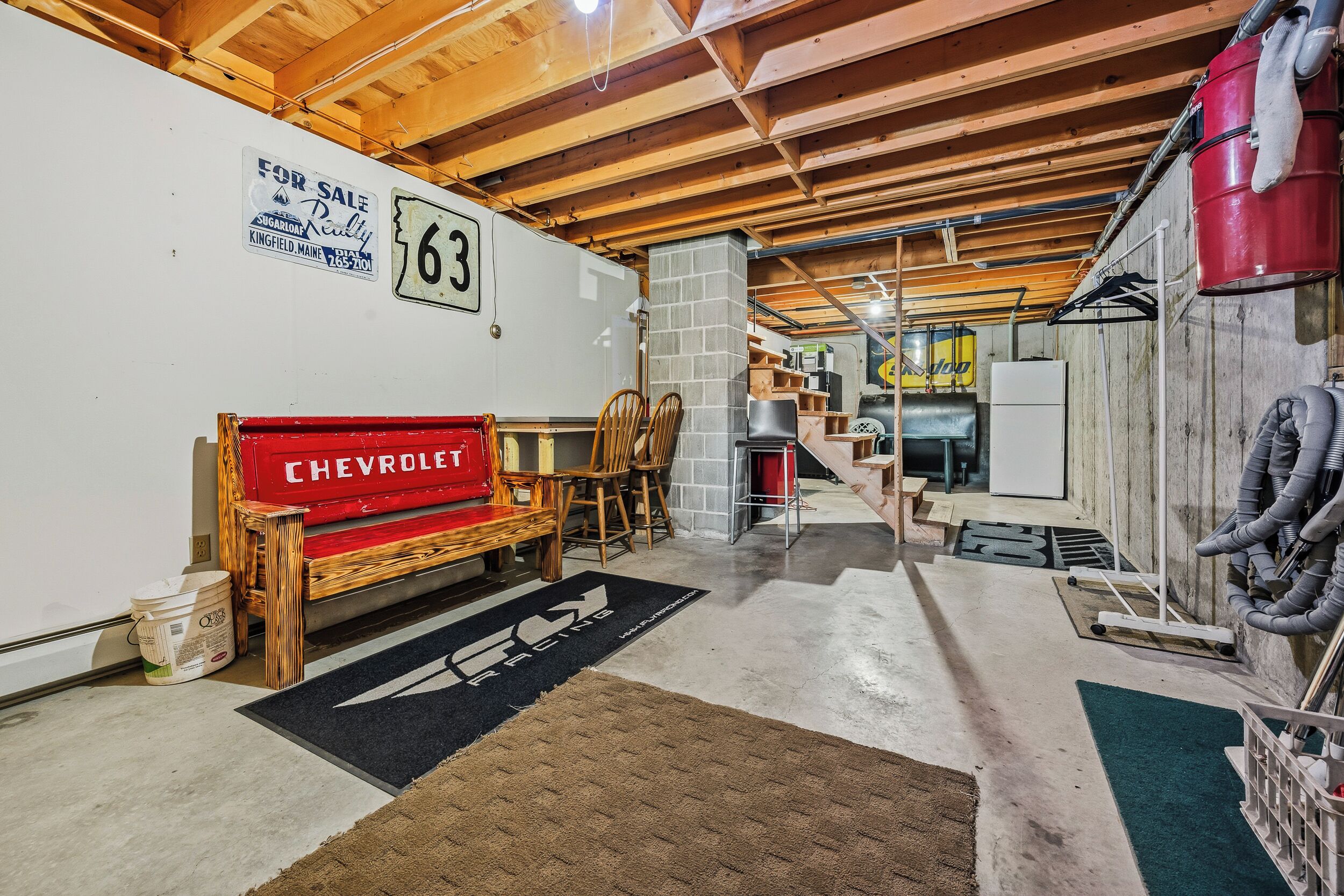 A garage with a wooden bench, a Chevrolet sign, a 'For Sale' sign, and a '63' sign.