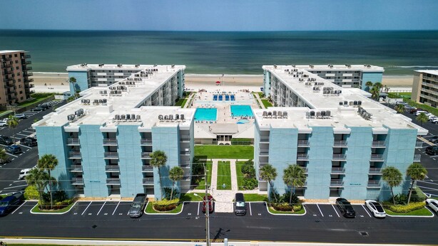 Een modern hotel met een centraal gelegen zwembad, meerdere balkons en uitzicht op het strand.