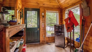 Cocina de cabaña de madera con un refrigerador, un lavamanos y una ventana con vista a un bosque.