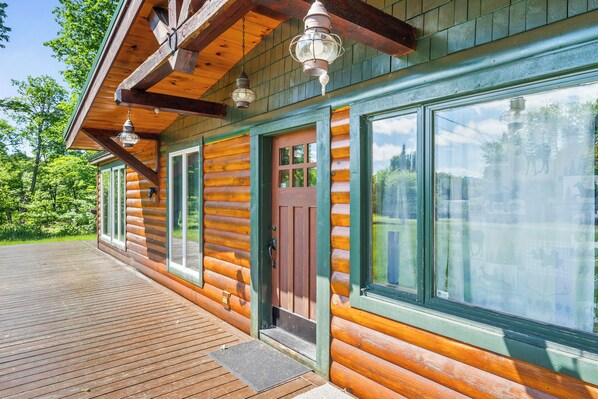 A log cabin with a wooden deck, large windows, and a door.